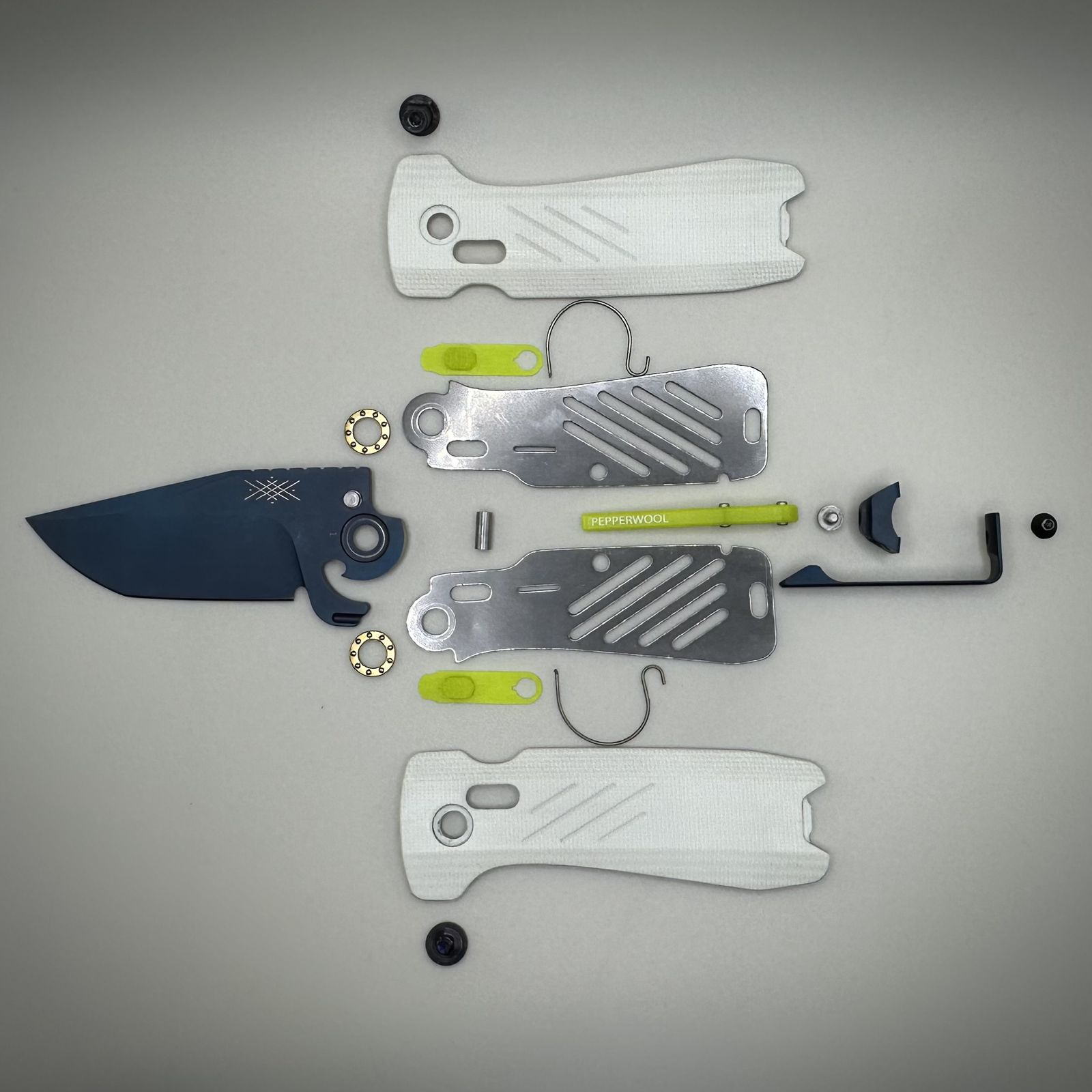 The MERINO MM laid out part by part at pre-production inspection: blade with kick tab, liners, bearings, pins and pocket clip